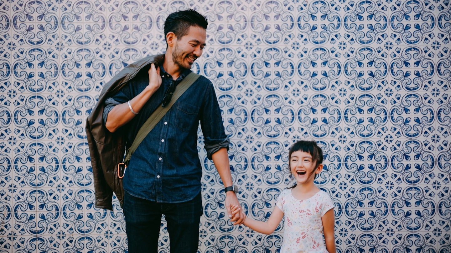 Japanese father and his preschool mixed race daughter on street of Portugal with azulejo tile wall